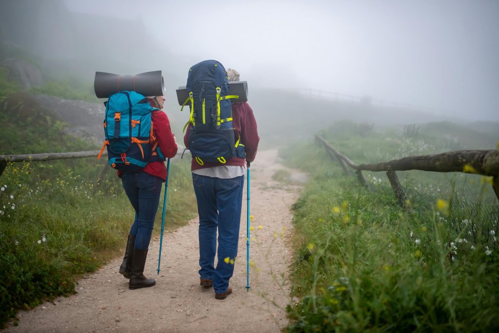 Two adults backpacking on a misty trail in Portugal. Outdoor adventure and leisure.
