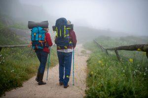Two adults backpacking on a misty trail in Portugal. Outdoor adventure and leisure.